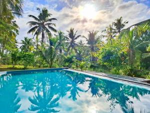 a swimming pool with palm trees in the background at Amandawa Eco in Gampaha