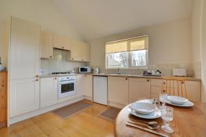 a kitchen with white cabinets and a wooden table with a table sidx sidx at 2 Bed in Attleborough oc-1277 in Old Buckenham