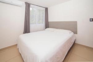 a white bed in a room with a window at condominio los mangos in Santa Cruz Huatulco