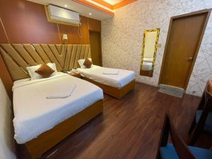 a hotel room with two beds and a mirror at Hotel Rosewood Uttara in Kāmarpāra