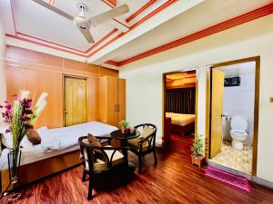 a bedroom with a bed and a table and a toilet at Hotel Rosewood Uttara in Kāmarpāra