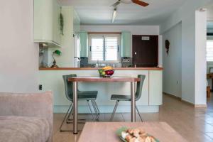a kitchen with a table and chairs in a room at Sunshine Royal Seacrest- Prime Location Paphos with Pool in Paphos