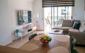 a living room with a table with a bowl of fruit on it at Sunshine Royal Seacrest- Prime Location Paphos with Pool in Paphos