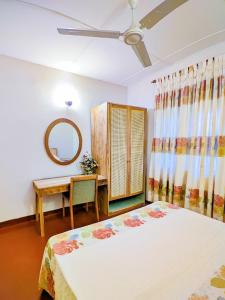 a bedroom with two beds and a table and a mirror at Amandawa Eco in Gampaha