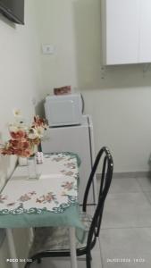 a table with a vase of flowers on it at Pousada Santos 4, kitnet confortável com ar condicionado in Londrina
