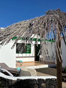 a white house with a thatched roof and chairs at CASA MACA sea view & beach front in Puerto del Carmen