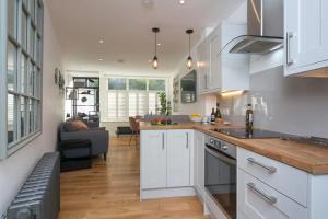a kitchen with white cabinets and a living room at Modern Town House Bangor City Centre in Bangor