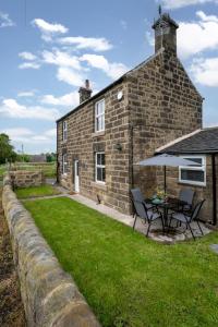 a brick house with a table and an umbrella at 2 Bed in Matlock oc-dcbeau in Crich
