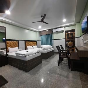 a bedroom with two beds and a desk and a television at Surakha INN LLP in Siliguri