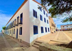 a white building with blue shutters on a street at La Esquineta de Tabarca in Tabarca