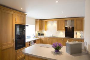 a kitchen with wooden cabinets and a table with purple flowers at 3 Bed in Low Row oc-ds1030 in Gunnerside