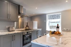 a kitchen with a bottle of wine and a bowl of fruit on a counter at 1 Bed in Gunnerside oc-ds1016 in Gunnerside
