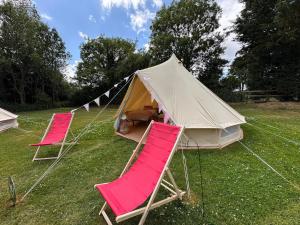two pink chairs and a tent in a field at Dovedale in Ashbourne
