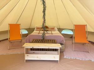 a tent with a bed and two orange chairs at Dovedale in Ashbourne