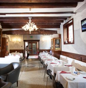 un comedor con mesas blancas y una lámpara de araña en Hotel Ca' D'Oro, en Venecia