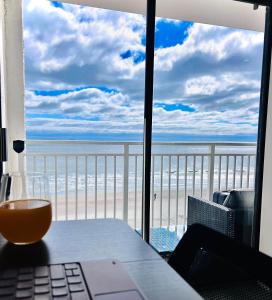 a laptop on a table with a view of the beach at Theo's Oceanfront Breeze in Myrtle Beach