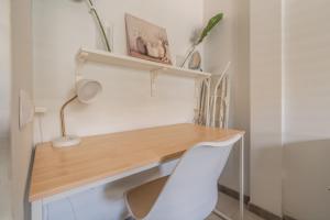 a desk with a white chair next to a desk with a lamp at The Energy Apartment in Caleta De Fuste +4 photos