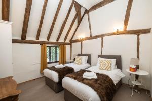 two beds in a room with white walls and wooden beams at Gildridge in Lewes