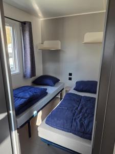 two beds in a room with blue pillows at Mobile Home Simplicity - Camp Diekirch in Gilsdorf