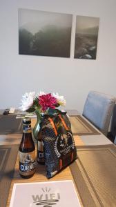 a table with a bottle of beer and a vase with flowers at Escapade en Ardenne - Appartement Sur Jardin Verdoyant in Bertrix