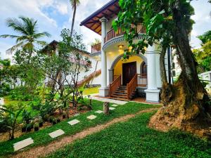 a house with a tree in front of it at Ever Breeze Villa Ahangama in Ahangama