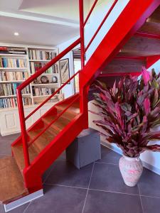 a red staircase in a room with a vase with a plant at Villa Vaihere in Orufara +7 photos