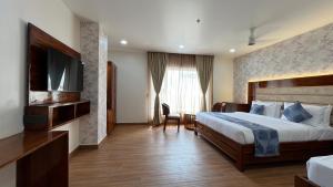 a hotel room with a bed and a television at Hotel Sudha Brahma in Tirupati