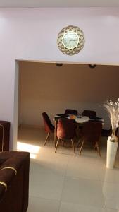 a dining room with a table and chairs and a clock at LEYLA house Résidence haut Standing in Bamako