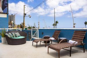 a patio with three chairs and a table on a balcony at Bahia Sol e Mar in Salvador