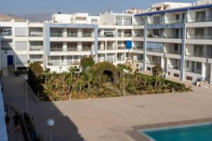 a large white building with a garden in front of it at Apartment in Adan Beach Residence With Pool in Aourir