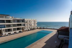 a swimming pool next to a building and the ocean at Apartment in Adan Beach Residence With Pool in Aourir