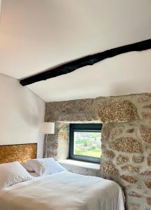 a bedroom with a stone wall with a bed and a window at Villa Seara - Casas da Vinha in Celorico de Basto +46 photos