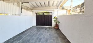 a garage with a black door and a potted plant at STO01 - Casa ampla em bairro tranquilo do Guarujá in Guarujá