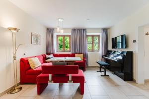 a living room with a red couch and a piano at Naturoase Mühlviertel in Sankt Johann am Wimberg
