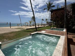 a hot tub next to a beach with the ocean at Hotel Pousada Pitinga in Arraial d'Ajuda