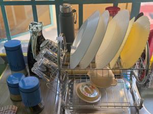 a dish drying rack with plates and a bottle of wine at Ibus Nawi homes in Lodwar