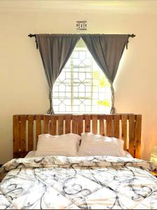 a bed in a room with a window at Nguruma house of travellers and tours in Arusha +8 photos