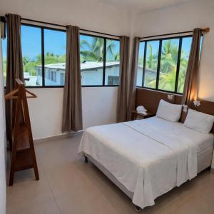 a bedroom with a white bed and large windows at Hotel Paseo del Sol in La Paz