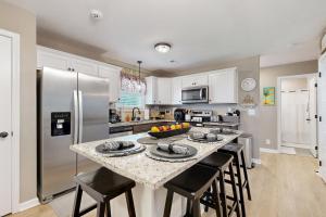 a kitchen with a counter with stools and a refrigerator at Gateway to Fort Campbell! Home w/ Furnished Deck in Clarksville