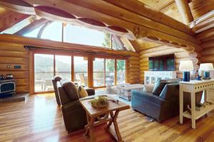 a living room with couches and a table in a cabin at Hot Tub + Dock! Waterfront Norris Lake Log Home in Elm Springs
