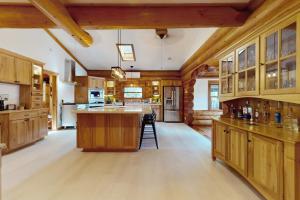 a large kitchen with wooden cabinets and a large island at Hot Tub + Dock! Waterfront Norris Lake Log Home in Elm Springs