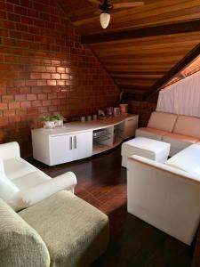 a living room with white furniture and a brick wall at Chalé Gravatá 2022 in Gravatá