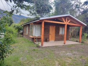 a small wooden cabin with a porch in a field at Cabaña irenio in Panguipulli