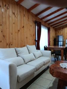 a living room with a white couch and a table at Cabaña irenio in Panguipulli