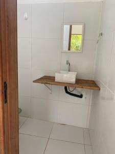 a white bathroom with a sink and a mirror at Casa Moreré in Ilha de Boipeba