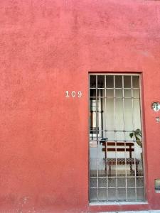 a red wall with a window with a gate at Casita Iluminada in Oaxaca City