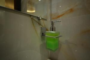 a bathroom with a green soap dispenser on a wall at The Gripa Hotels in Chitrakoot