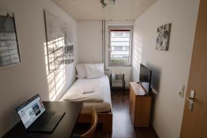 a small room with a bed and a desk with a laptop at Hotel Spilburg in Wetzlar
