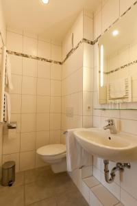 a white bathroom with a sink and a toilet at Huberwirt am Kellerberg in Wasserburg am Inn +38 photos