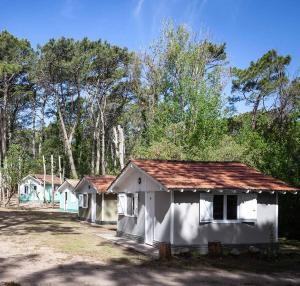 a row of white buildings with trees in the background at Bungalow Caravan in Villa Gesell +8 photos
